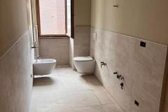 Erretre Ceramiche ristrutturazione appartamento a Milano zona piazzale Siena, bagno con: muri beige, bidet e water sospesi di colore bianco  in fase di costruzione.