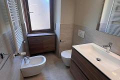 Erretre Ceramiche ristrutturazione bagno appartamento a Milano zona Piazzale Siena, bidet e water con: mobile bagno, lavandino di colore bianco e specchio rettangolare in vetro.