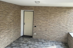 Vista ingresso villetta unifamiliare a Marcallo, con pareti rivestite con piastrelle in pietra di colore giallo Sinai e piastre, e, i pavimenti rivestiti con piastrelle in grès porcellanato di colore grigio