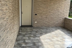 Ingresso villetta unifamiliare a Marcallo con pareti esterne rivestite con piastrelle in pietra color giallo Sinai e i pavimenti rivestiti con piastrelle in grès porcellanato di colore grigio