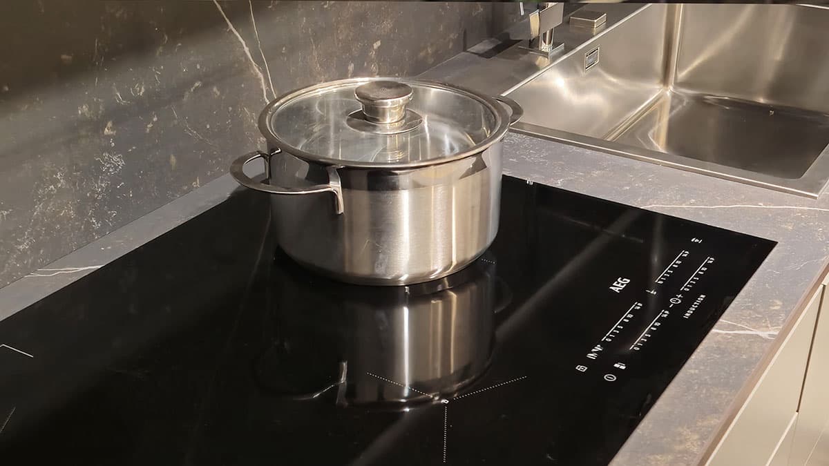 Dettaglio Piano Cottura a Induzione AEG sulla cucina Elmar Modello Slim. Top e schienale in marmo scuro con venature.